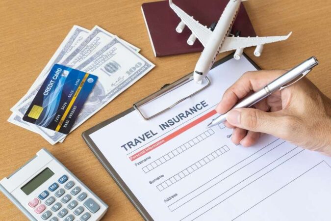Une personne remplit un formulaire de souscription pour les assurances voyage organisé avec une carte bancaire et un avion miniature à proximité.