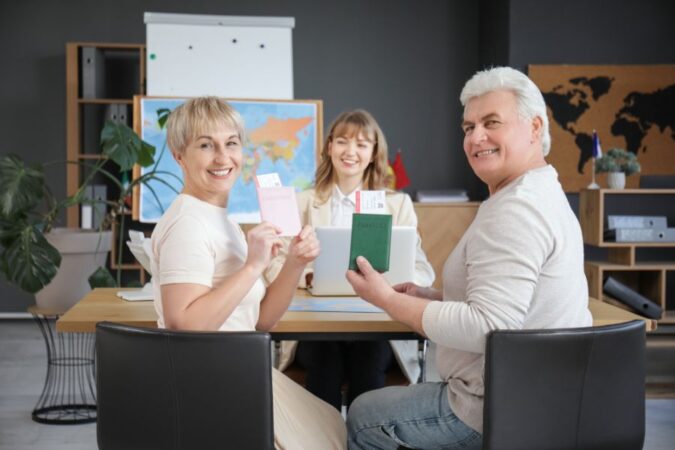 Un couple de seniors sourit en montrant ses passeports dans une agence de voyage locale.